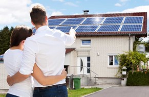 Par foran hus med solceller på taket