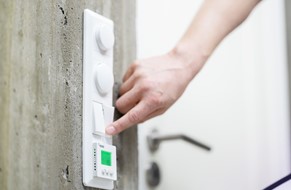 Hånd som trykker på lysbryter over termostat